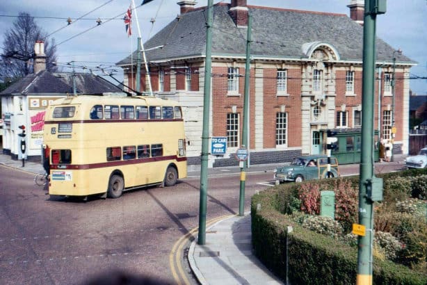 Colour photo of a yellow trolleybus taking a right turn past the old Pokesdown fire station.