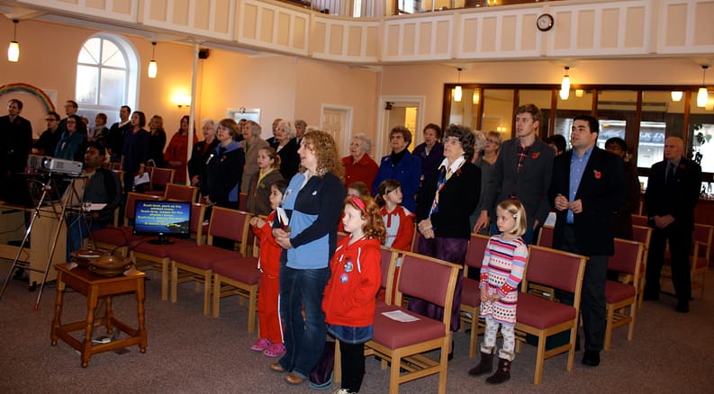 colour photo of people stood singing in church